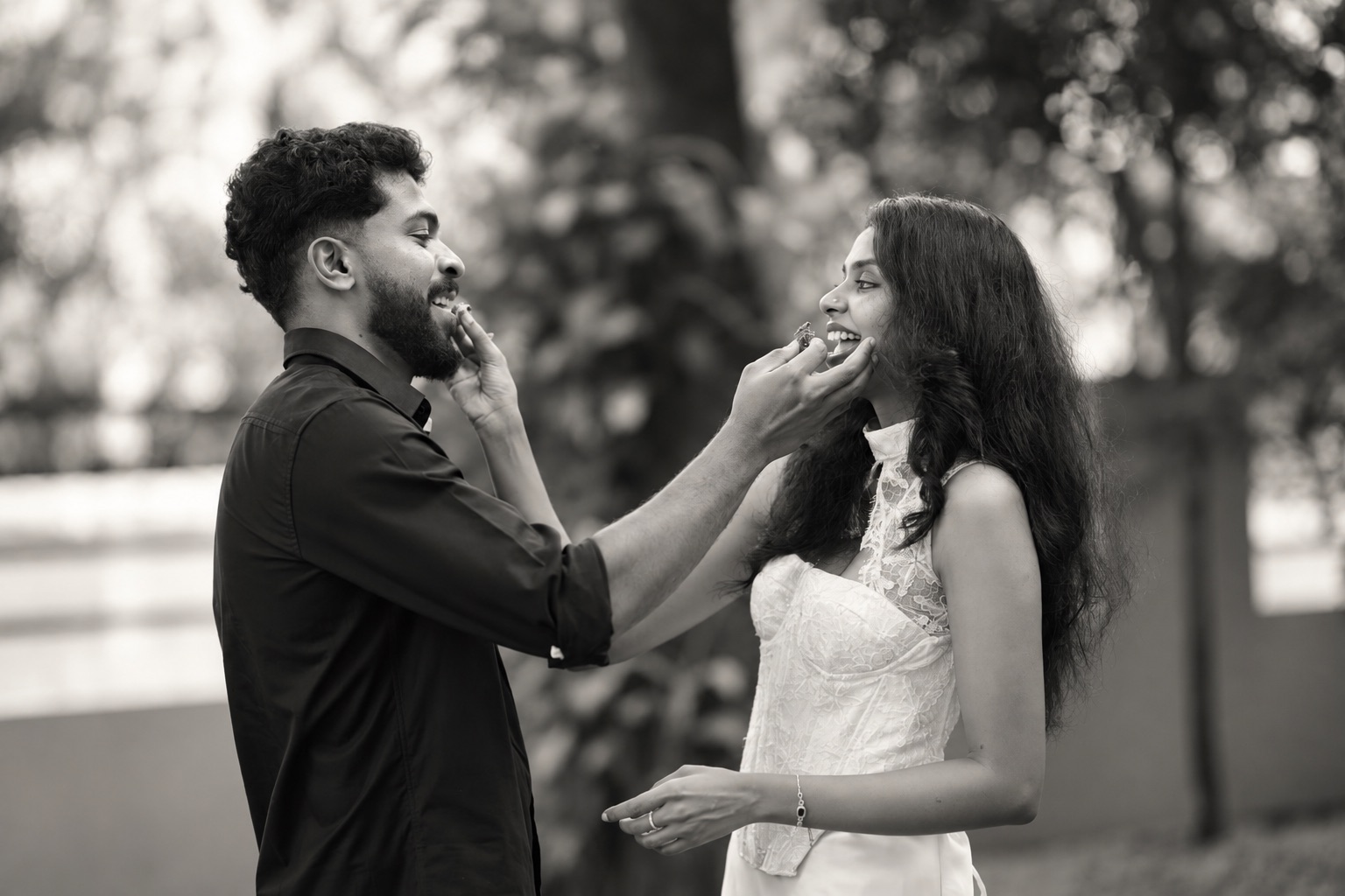 Abhijith and Aiswarya laughing as they feed each other sweets